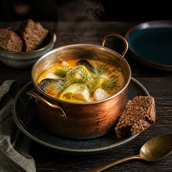 Fischsuppe im Kupfertopf mit Muscheln und Dill