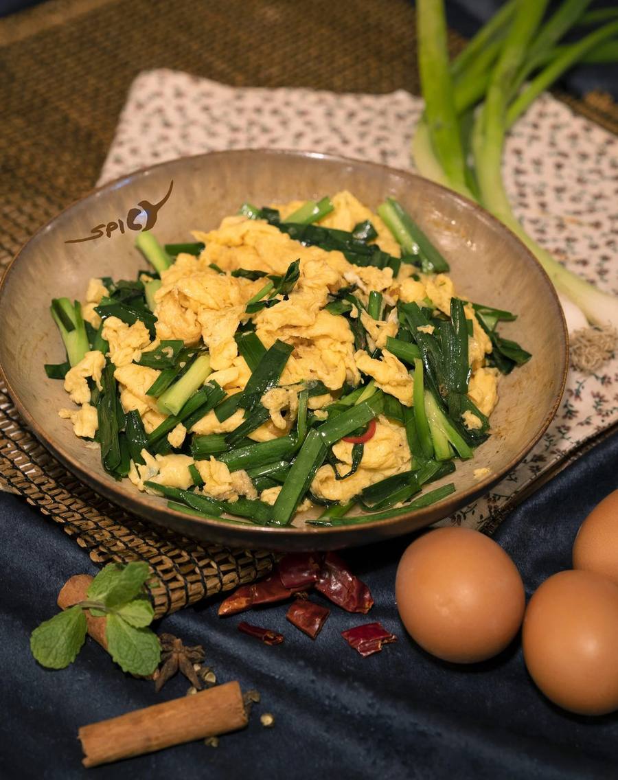 Bärlauch mit Ei in einer Steingutschale, daneben Eier und Frühlingszwiebeln